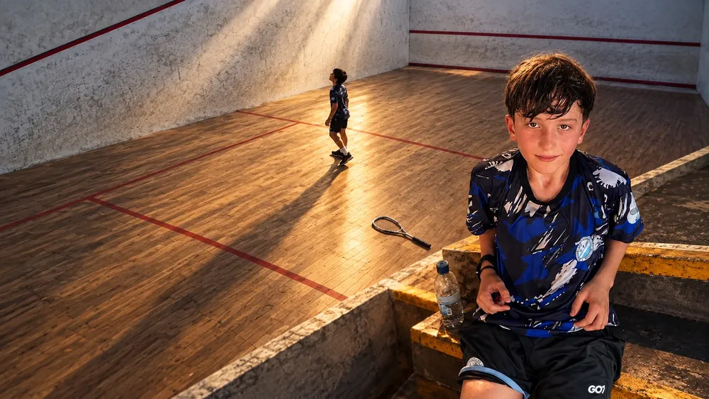 Joven en cancha de squash al atardecer